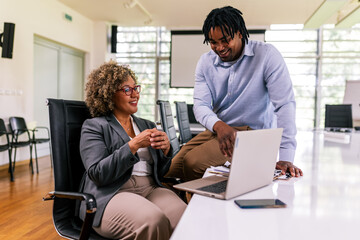 Two multiracial business colleagues working together in the office on laptops and tablets