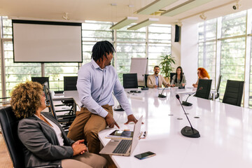 Two multiracial business colleagues working together in the office on laptops and tablets