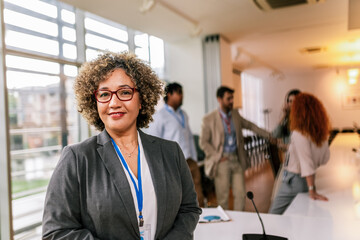 Portrait of older African American businesswoman standing in front of her colleagues.