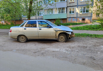 A gray wrecked car parked on the side of a city road