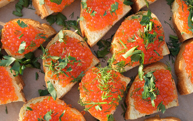 red salmon caviar on white bread sprinkled with green parsley and dill