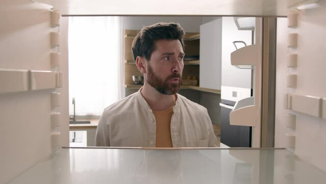 POV point of view from inside refrigerator Caucasian hungry man adult sad upset disappointed male guy looking for good twice open empty fridge no food without products crisis delivery supermarket