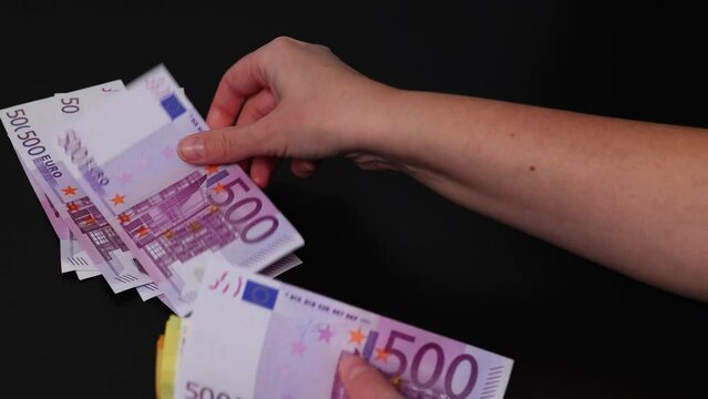 Close-up woman's hands counts different euro money banknotes. Puts money in different stacks at face value.