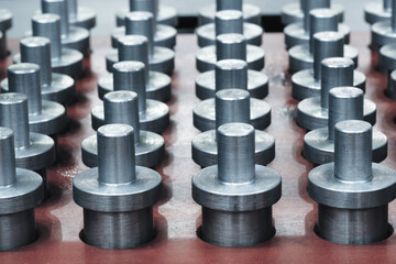 A row of metal cylinders with a hole in the middle. The cylinders are all the same size and shape