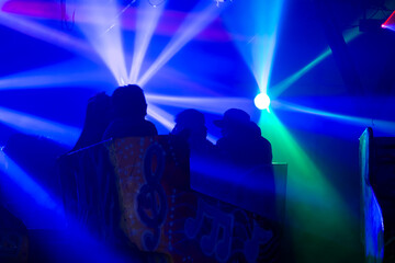 Luces de colores neon y siluetas negras de gente dentro de un juego mecanico en la espera de el...