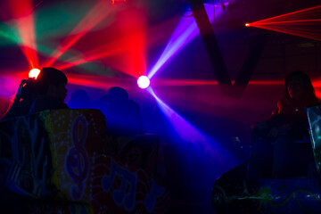 Luces de colores neon y siluetas negras de gente dentro de un juego mecanico en la espera de el...