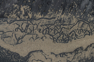 Intricate Patterns in Sand and Black Sediment