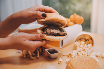 fast food, people and unhealthy eating concept - close up of woman hands holding hamburger or...