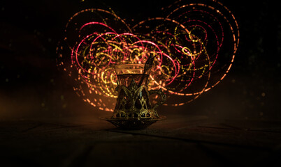 Arabian tea in glass with eastern snacks on a carpet on dark background with lights and smoke. Eastern tea concept. Empty space. Selective focus.