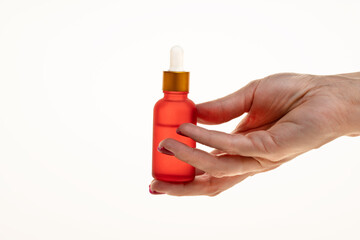 Woman's hand holding a red dropper bottle with serum for face or body smoothing and anti-aging