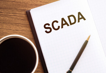 Notepad With the Word SCADA Next to a Cup of Coffee