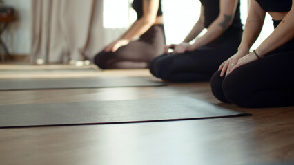 Three beautiful slim women spreading out yoga mats before training in studio. Media. Girls having...