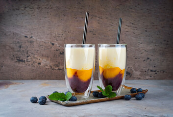 Traditional striped milk shake with mango, blueberries and buttermilk served in a glass as close-up...