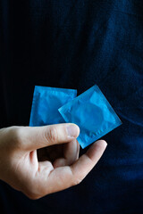 Young man holding two condoms safe contraception