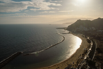 View from above of the sunset at Las Teresitas beach with yellow sand. Sun shine reflects in the sea during the sunset at beautiful beach near the Santa Cruz de Tenerife city, Canary Islands