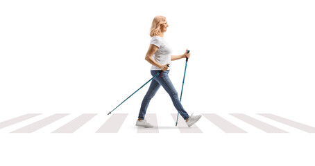 Full length profile shot of a middle aged woman with walking poles crossing a street