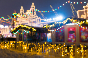 Defocused colorful houses on Christmas Fair in winter with lots of lights and bokeh on snowy evening