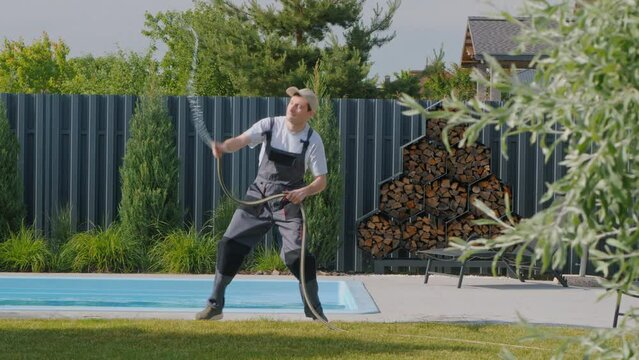 Gardener doing crazy dance with garden hose, watering lawn