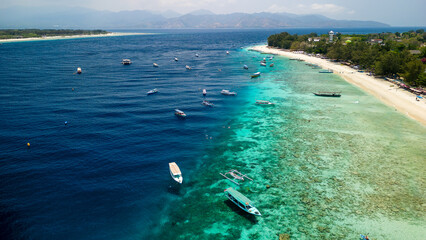 Snorkelling and SCUBA tour boats on the reef edge next to the main beach of Gili Trawangan, Indonesia