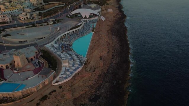 Malta National Aquarium aerial in the morning, during sunrise. Coastal road andmodern building. Rocky beach and Mediterranean sea. St. Paul's Bay, Malta. High quality 4k footage