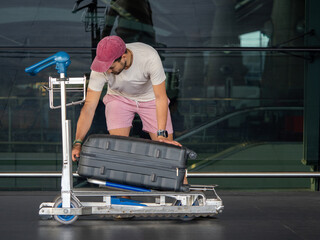 Man Adjusting Suitcase on Airport Luggage Trolley