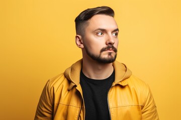 Fototapeta premium A man with a beard and a yellow jacket is standing in front of a yellow wall