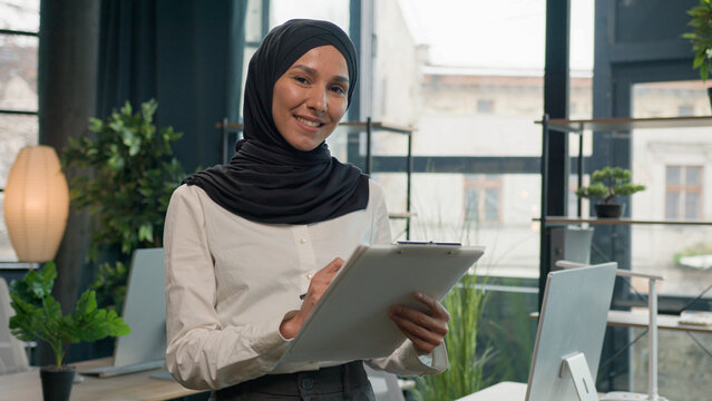 Happy muslim Islam woman Arabian girl in hijab HR manager secretary with paper tablet write notes sign data in note tablet writing to-do list business ideas successful businesswoman planning workflow - Powered by Adobe