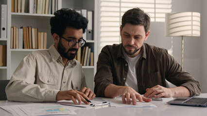 Two multiethnic colleagues businessmen business coworkers at office discuss financial data project...