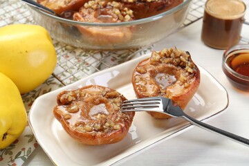 Delicious quinces baked with honey and walnuts on white table