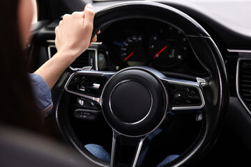 Woman holding steering wheel while driving her car, closeup