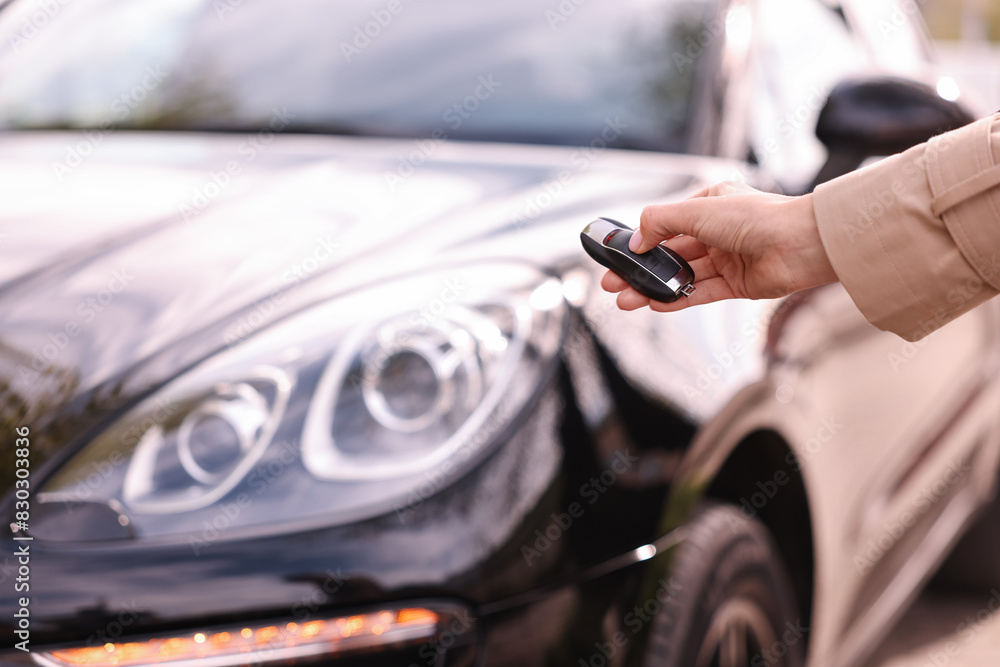 Wall mural woman holding car flip key near her vehicle outdoors, closeup