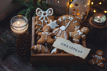 Wooden vintage box with homemade delicious gingerbread cookies decorated with white icing. Cozy home atmosphere, fairy lights, fir tree branches. Handmade zero waste gift for Christmas or New Year - Powered by Adobe