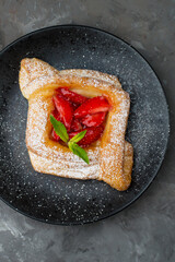Puff pastry with strawberries on a dark background, top view.