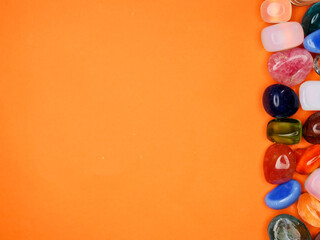 A colorful assortment of gemstones and crystals are arranged on a bright orange background. The variety of colors and shapes create a visually striking and vibrant scene. Concept of natural beauty