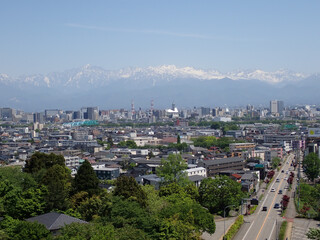 Fototapeta premium 5月新緑の呉羽山富山県道44号富山高岡線を跨ぐ遊歩道吊橋から北アルプス剱岳立山連峰富山市街地を望む