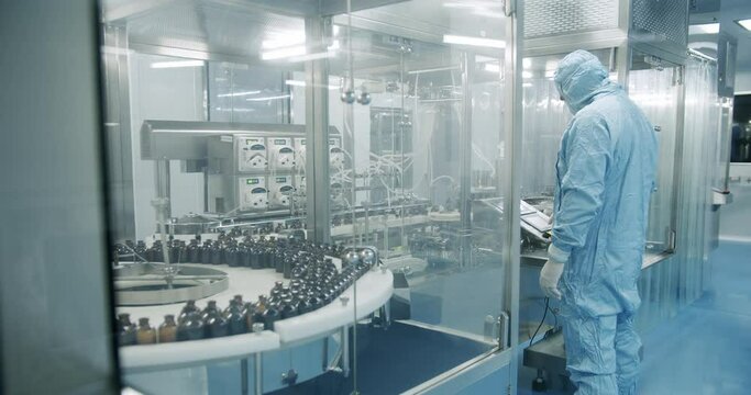 Sterile Pharmaceutical Manufacturing Laboratory where Scientists in Protective Coveralls. Factory Cleanroom. Pharmaceutical, Scientists in Sterile Protective Clothing Work on a Modern Laboratory.