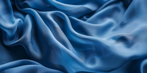 Fototapeta premium Blue fabric with delicate folds. Silk satin fabric backdrop with copy space.