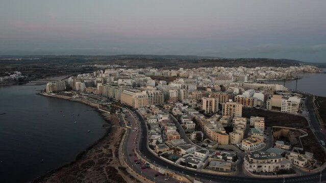 Qawra cityscape in the early morning, during the Sunrise and golden hour. Buildings, construction sites. Aerial. High quality 4k footage