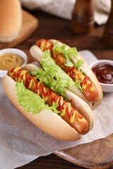 Tasty hot dogs with lettuce, ketchup and mustard on table