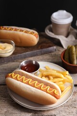 Delicious hot dog with ketchup, mustard and French fries on wooden table, closeup