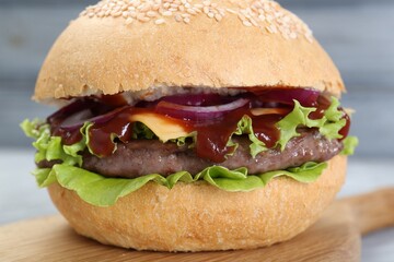 Delicious cheeseburger with lettuce, onion, ketchup and patty on blurred background, closeup