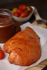 Raw marinated chicken fillets on wooden table, closeup