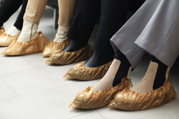 Women wearing shoe covers onto different footwear indoors, closeup