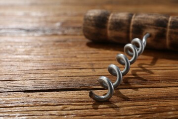 One corkscrew on wooden table, closeup. Space for text