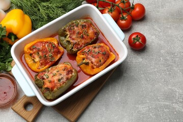 Tasty stuffed peppers in dish and ingredients on grey table, above view. Space for text
