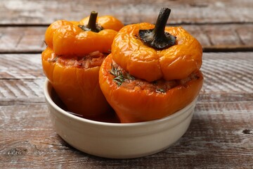 Tasty stuffed peppers in bowl on wooden rustic table, closeup