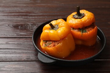 Tasty stuffed peppers in pan on wooden table, closeup. Space for text