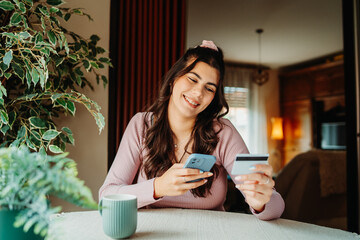 One young caucasian woman is buying online on her laptop using credit card from her home	