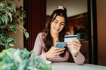 One young caucasian woman is buying online on her laptop using credit card from her home	