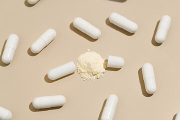 Pattern of white capsules pills with active ingredient powder on a beige isolated background. A concert of pharmacy, medicinal products, dietary supplements and tablets